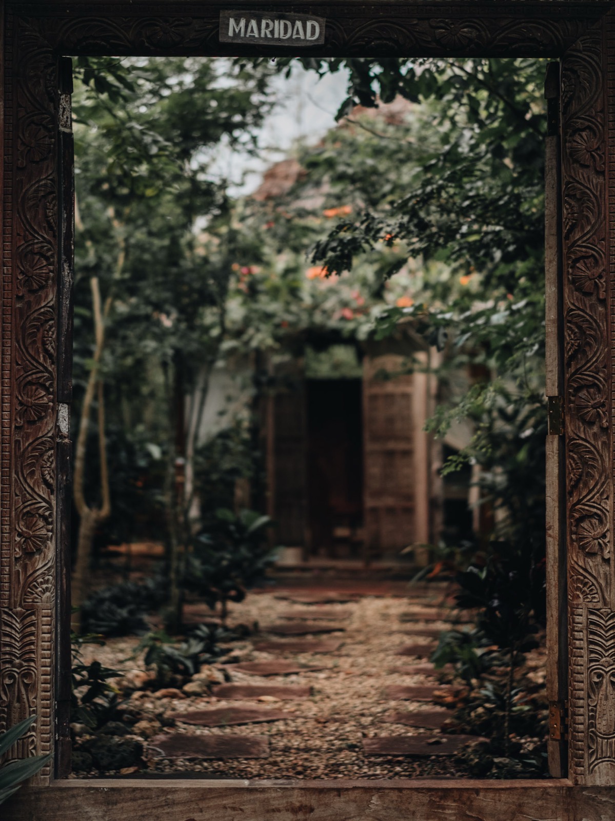 Ornate carved wooden doorway leading to a lush tropical garden path on the Zanzibar coast