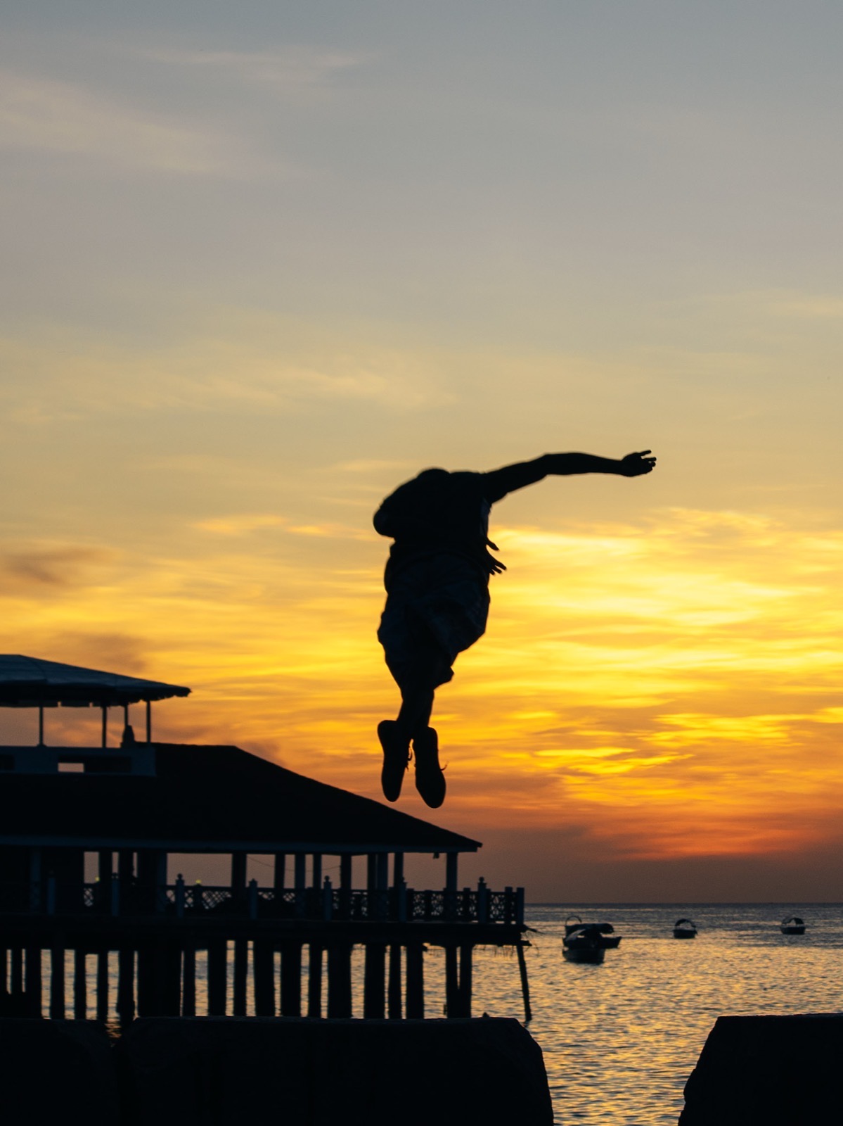Silhouette of a person jumping against a vivid orange and red sunset over the Indian Ocean from Nungwi beach
