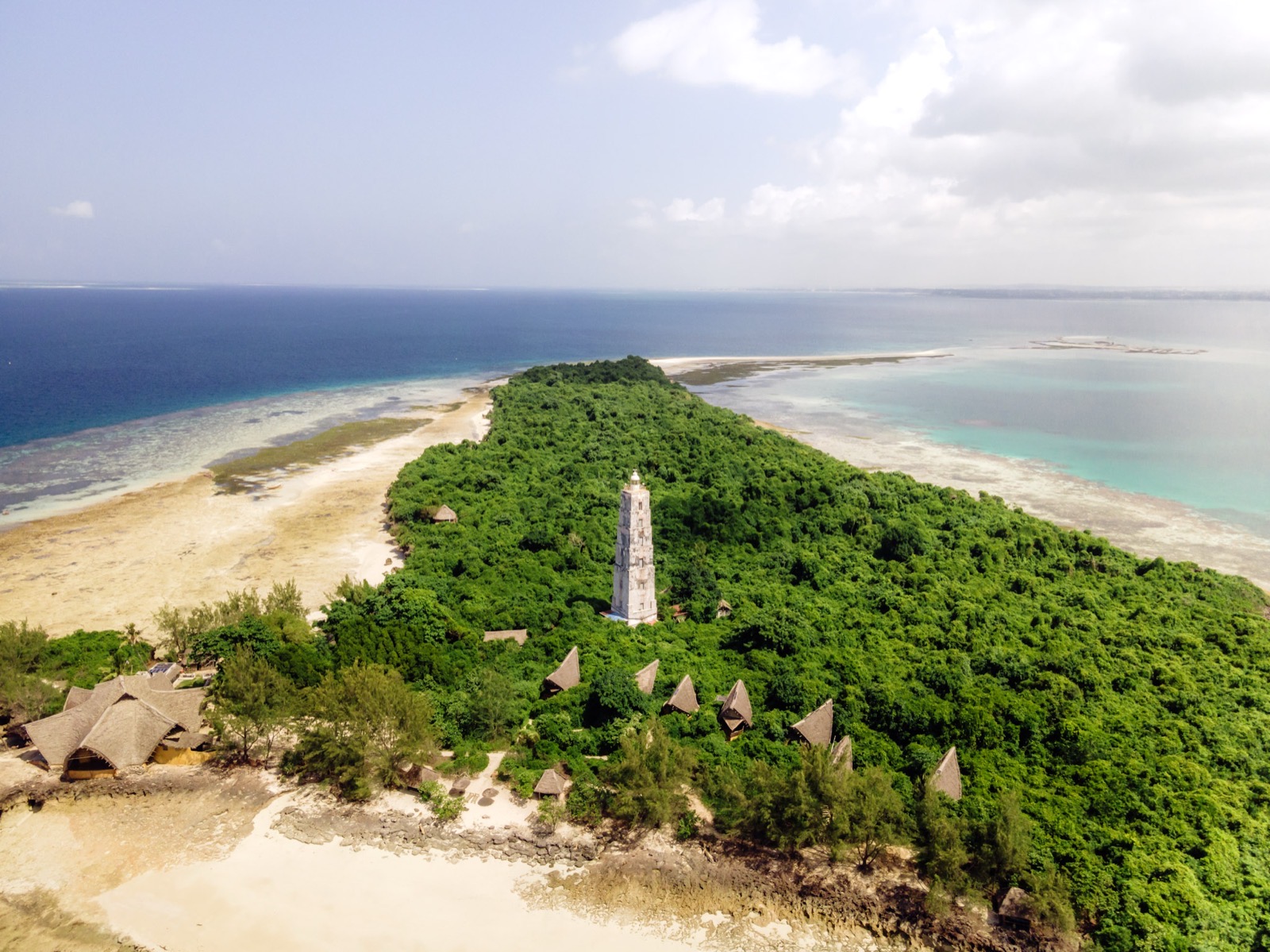 Aerial view of a small tropical island with lighthouse and thatched bungalows on Zanzibar's north coast